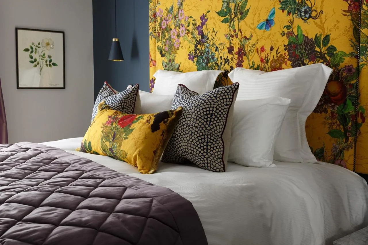 a bedroom with a bed with pillows and a painting at The Gonville Hotel, a member of Radisson Individuals in Cambridge