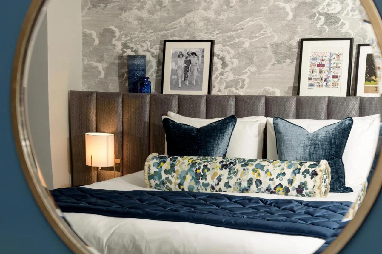 a mirror reflecting a bed with blue pillows at The Gonville Hotel, a member of Radisson Individuals in Cambridge