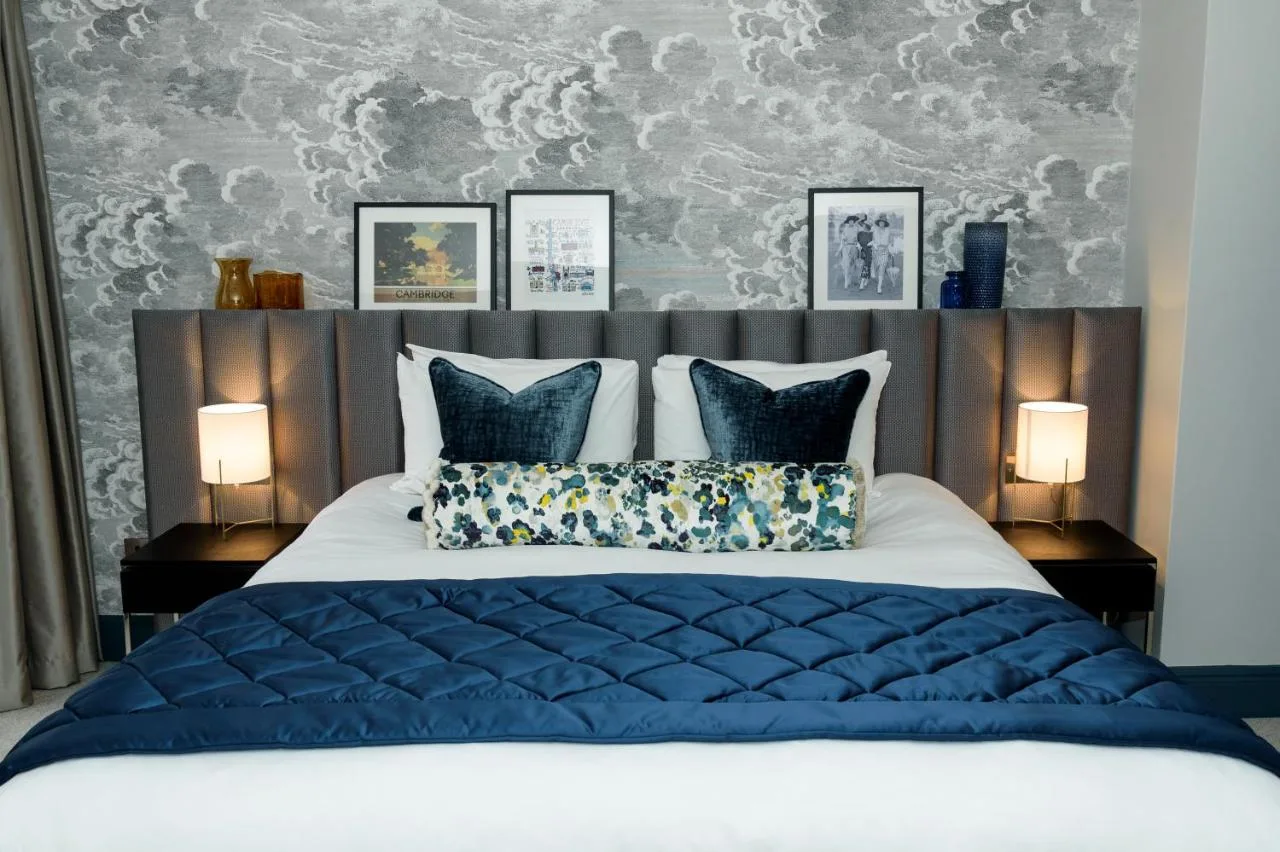 a bedroom with a large bed with blue pillows at The Gonville Hotel, a member of Radisson Individuals in Cambridge